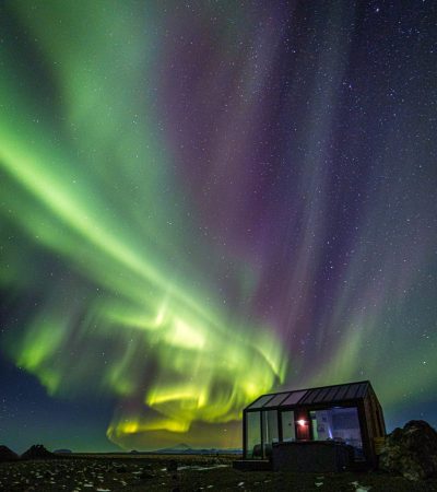 Glass Cottage in Südisland mit Nordlichtern
