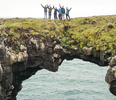 Junge Reisende auf dem beeindruckenden Steinbogen über dem Meer in Island.